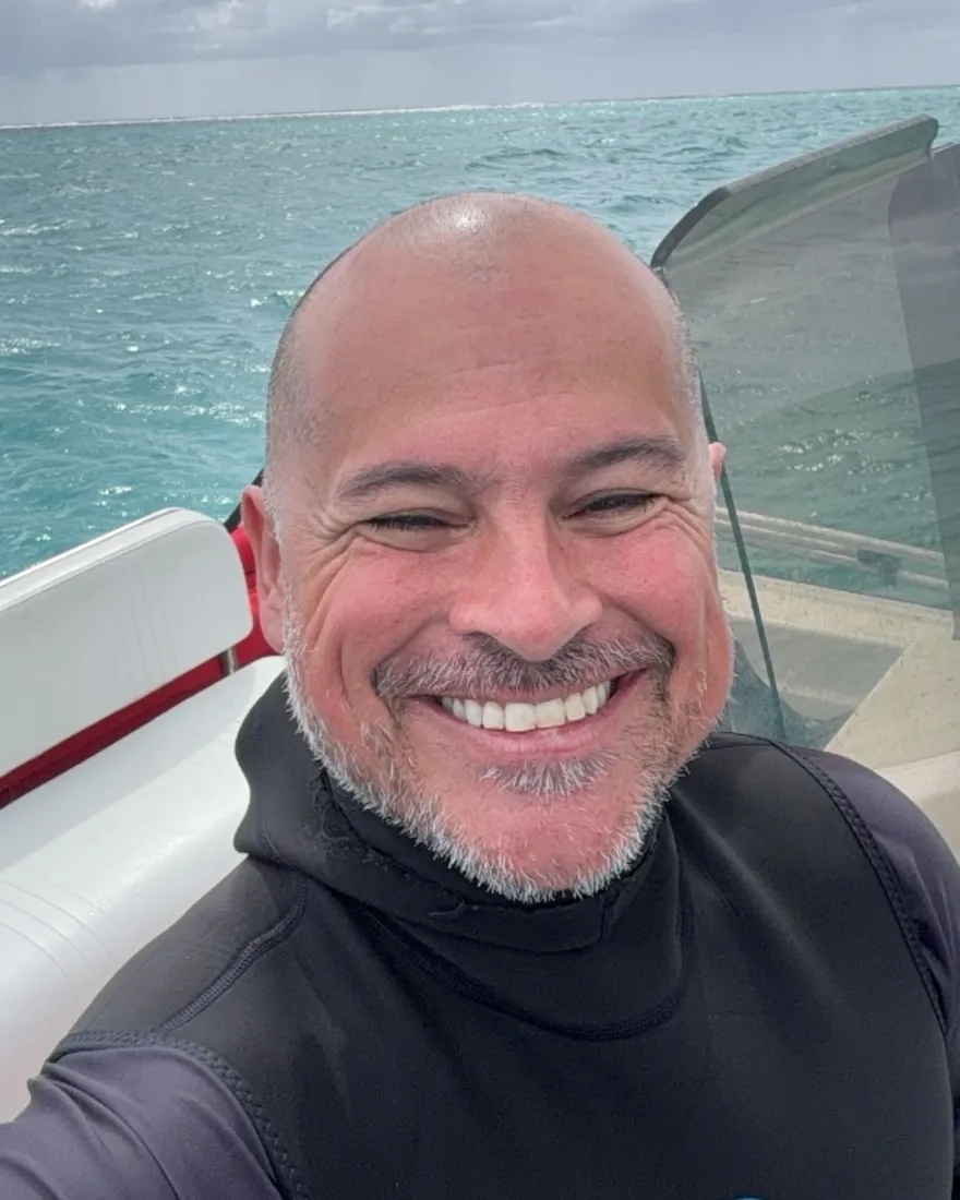 Nicolás Filauri sonriendo en un bote, con el mar turquesa detrás